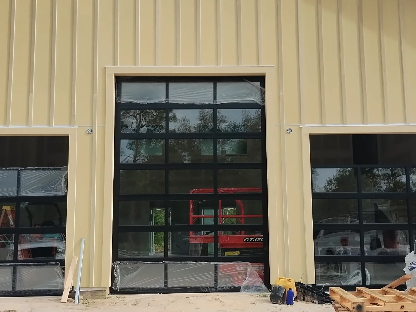 A garage door technician working on a residential commercial garage doors job — mid-task, hands, tools and the work itself in sharp focus, the rest of the space softly out of focus